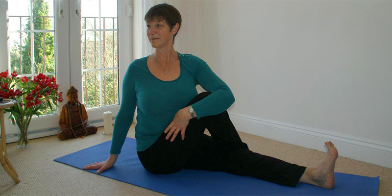 Cathie in her yoga teaching space in seated twist posture – lengthens and releases spine, massages abdominal contents and opens chest.