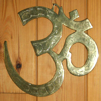 OM symbol in brass on wood background. Om is the sacred symbol that represents All That Is. The OM is considered to be the primordial sound.