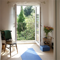 Cathie's yoga teaching space at her home. Sunshine floods in through open casement doors and a Juliet balcony. Flowers and candles bring a sense of calm peace to this space.